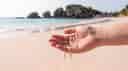 A hand touching sand on a beautiful beach.