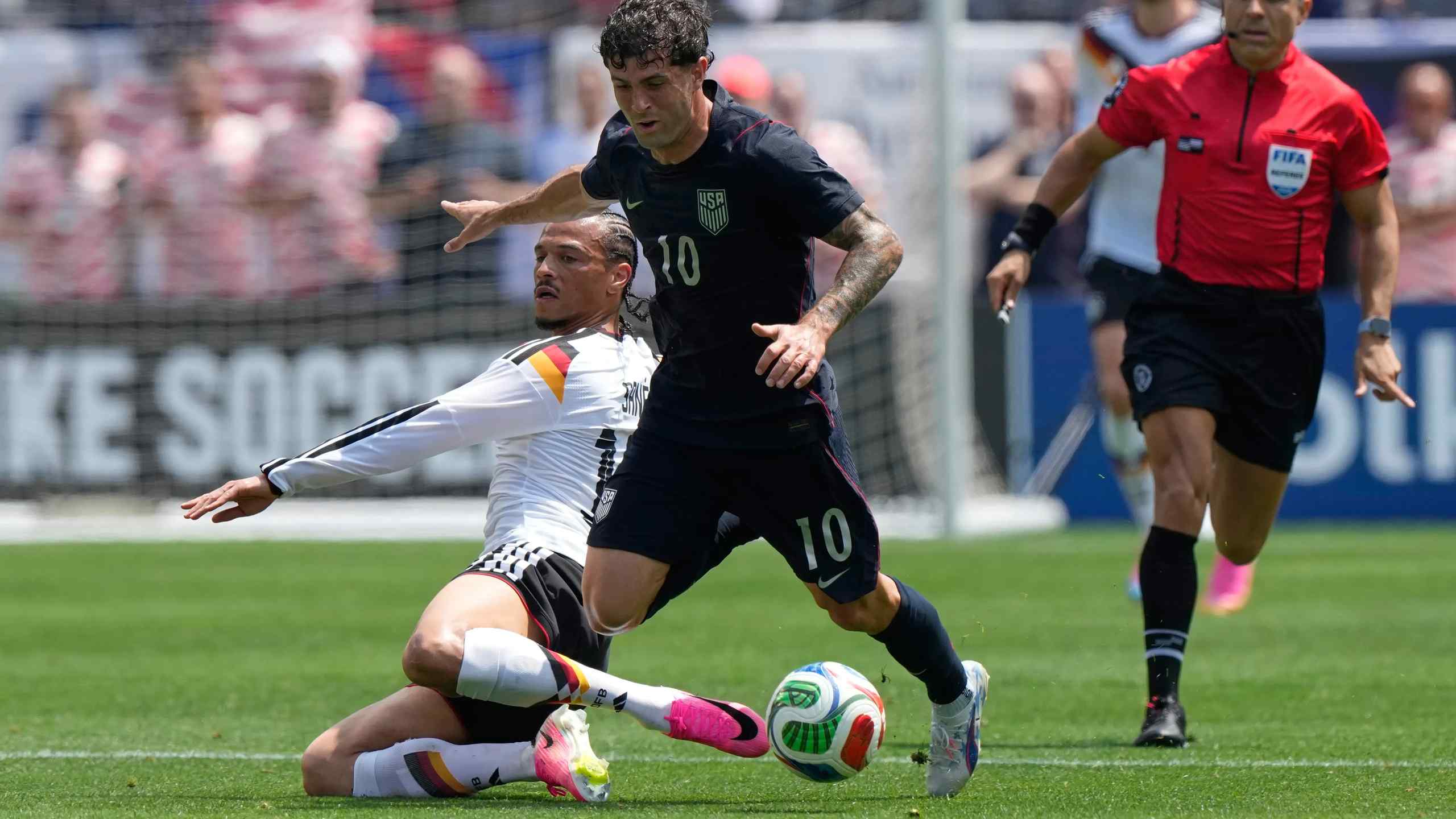 The USMNT's Christian Pulisic dribbles past Germany's Leroy Mane.