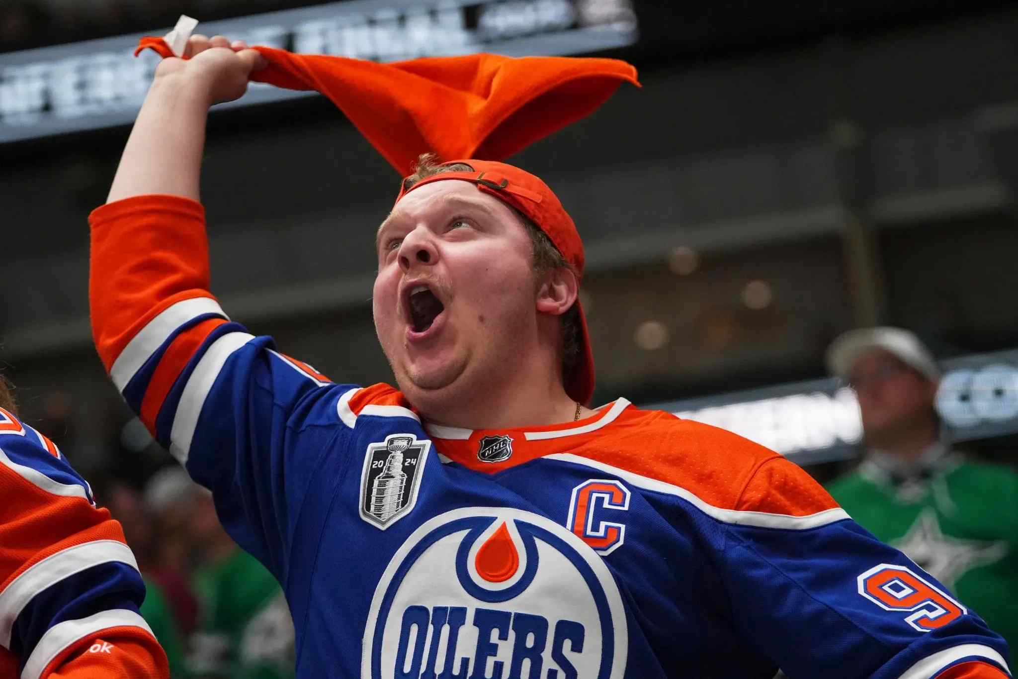 Edmonton Oilers fan waving an orange towel while cheering during the 2025 Stanley Cup Playoffs.
