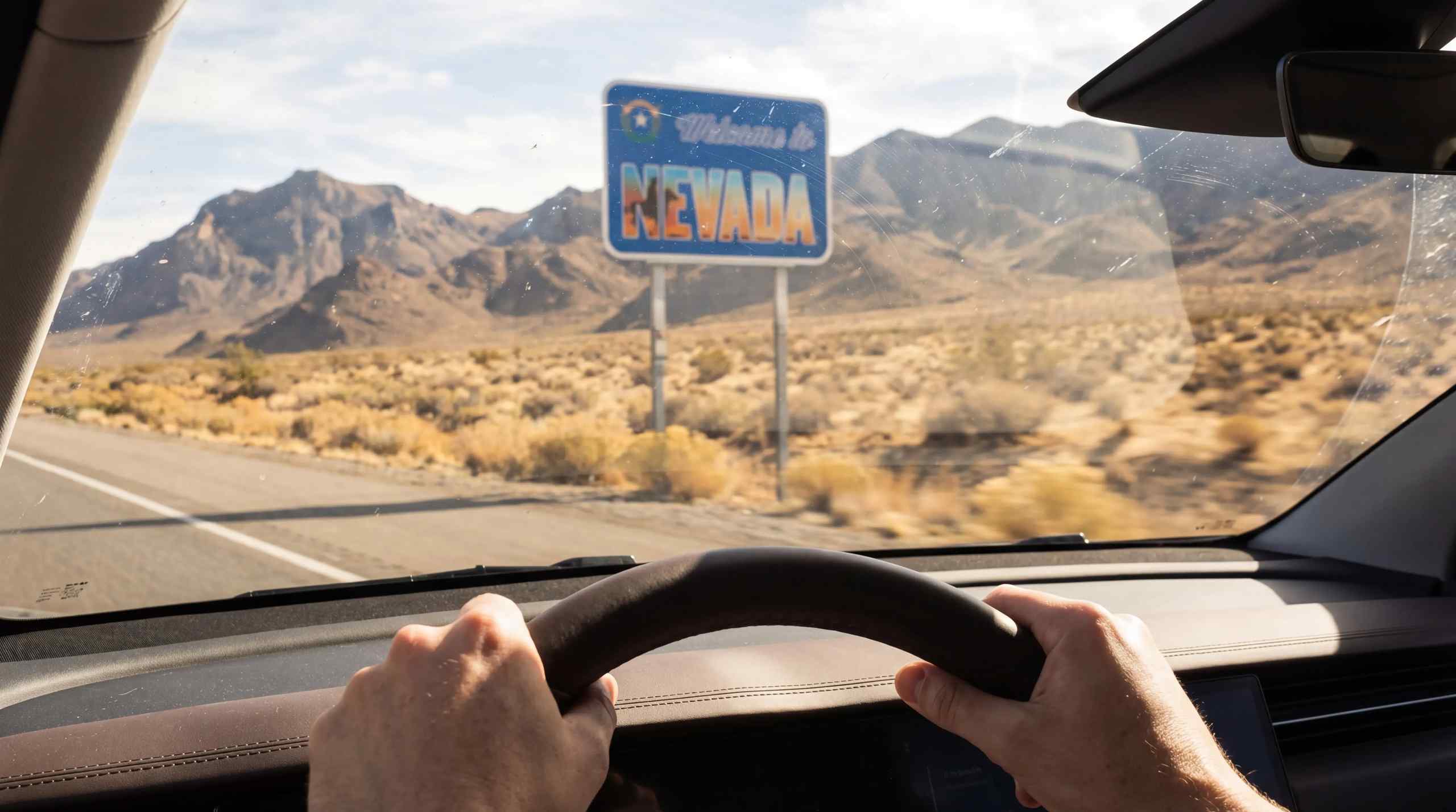A car approaching a sign that reads Welcome to Nevada.