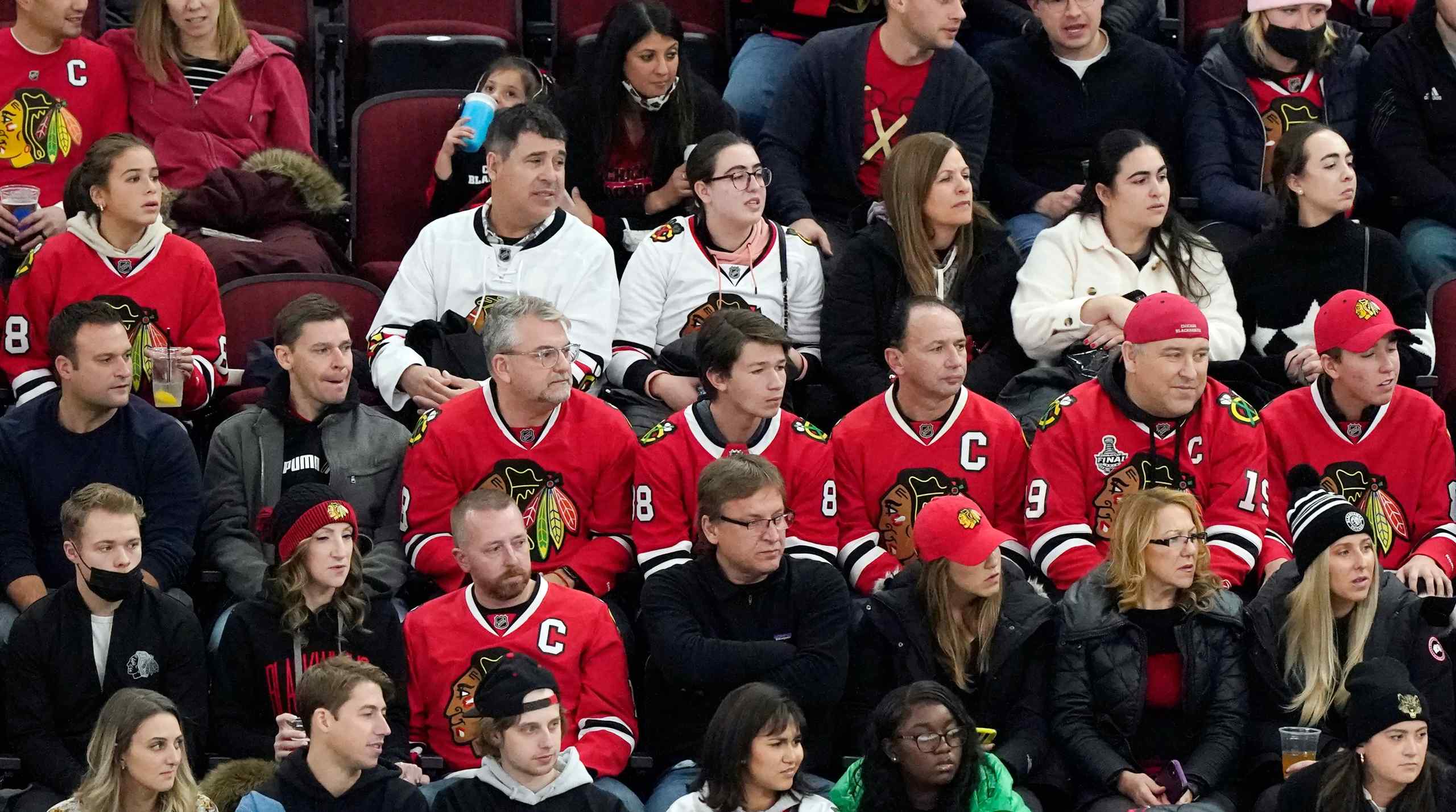 Chicago Blackhawks fans wearing jerseys and looking sad at the game.