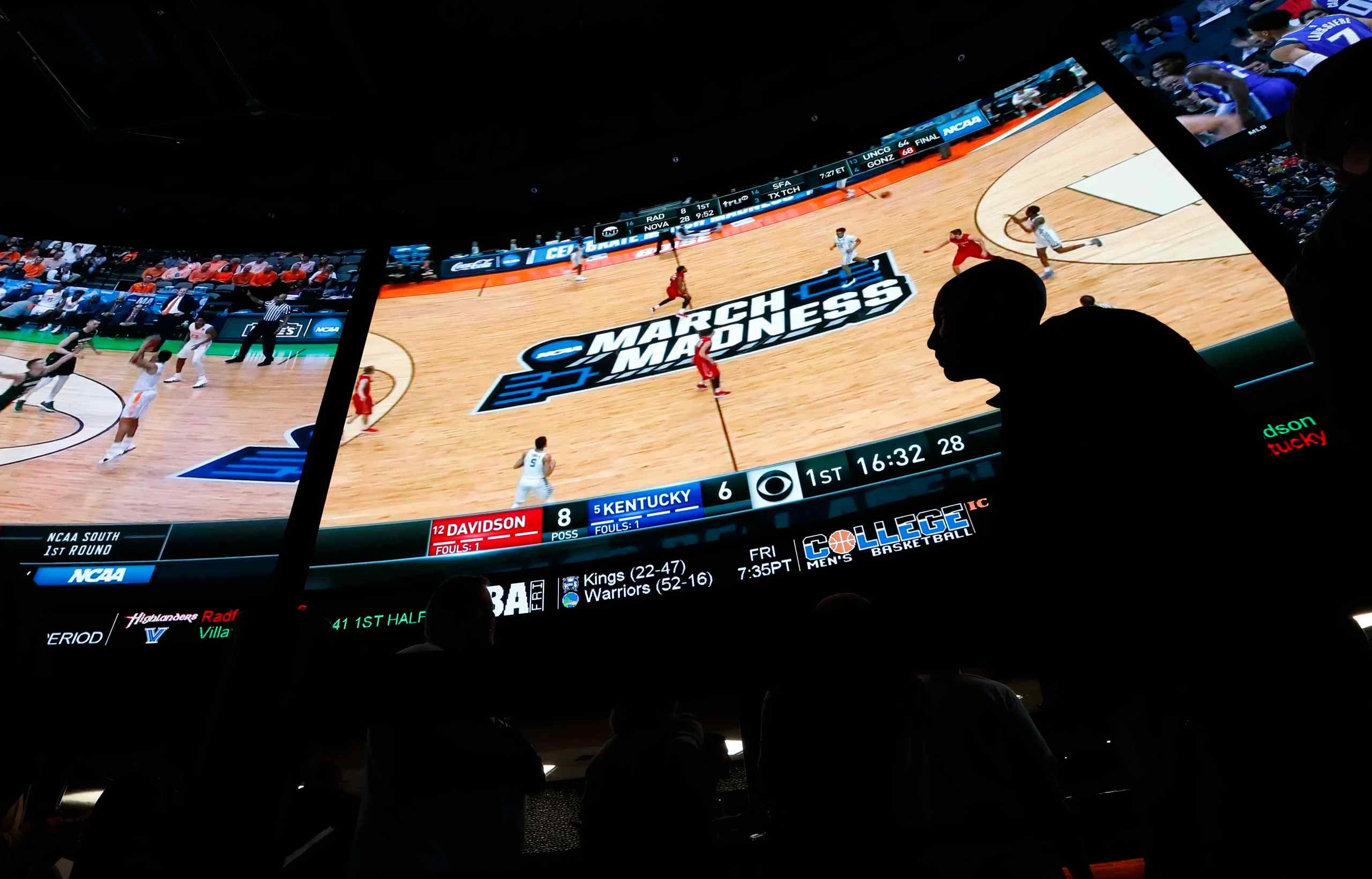 A TV screen in a sports book that's displaying March Madness.