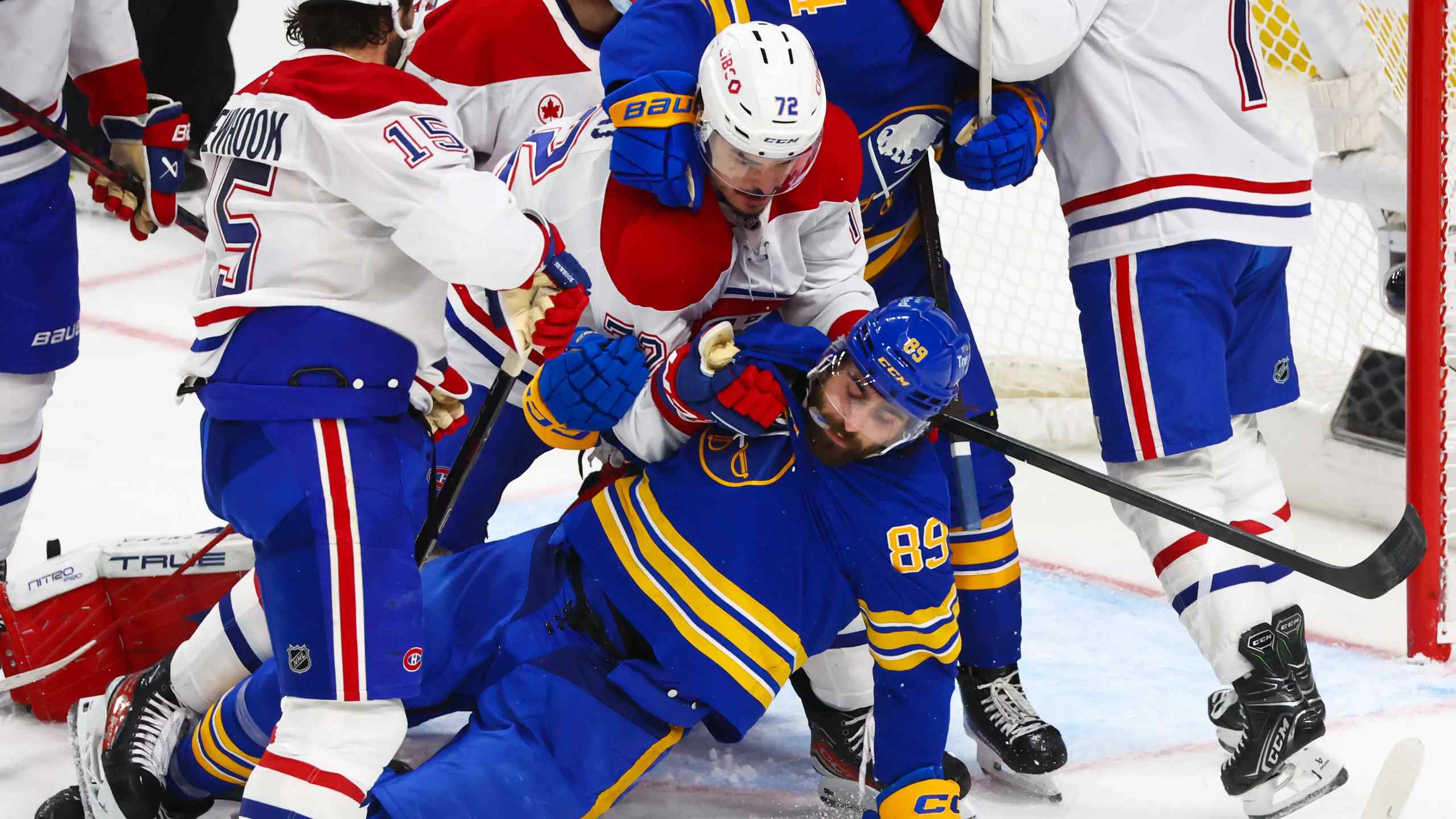hockey players wrestling in the crease