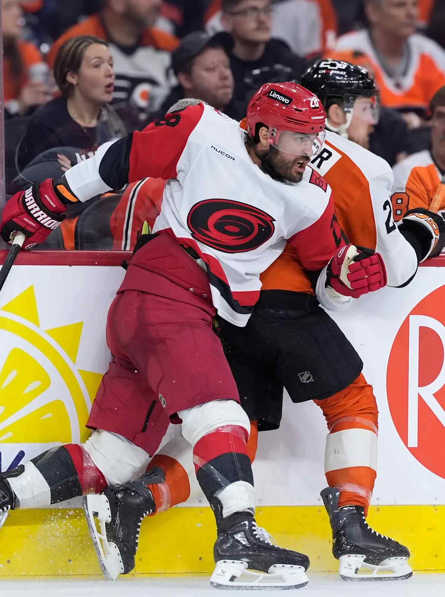 two hockey players shoving and skating on the boards