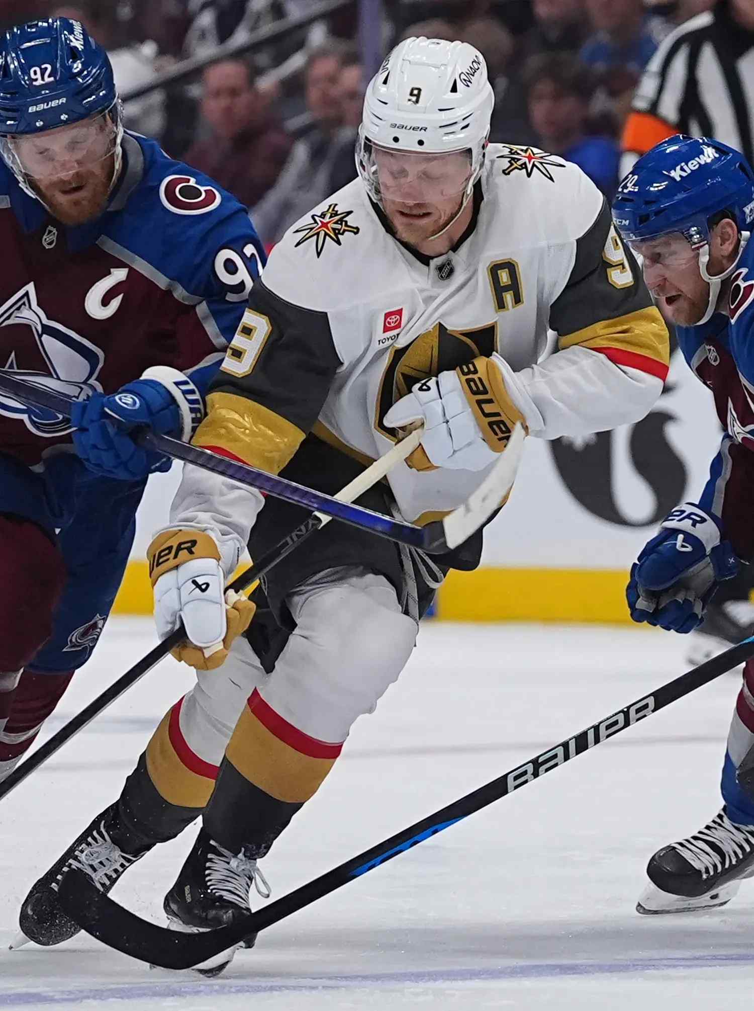 Vegas player skating between avalanche defenders