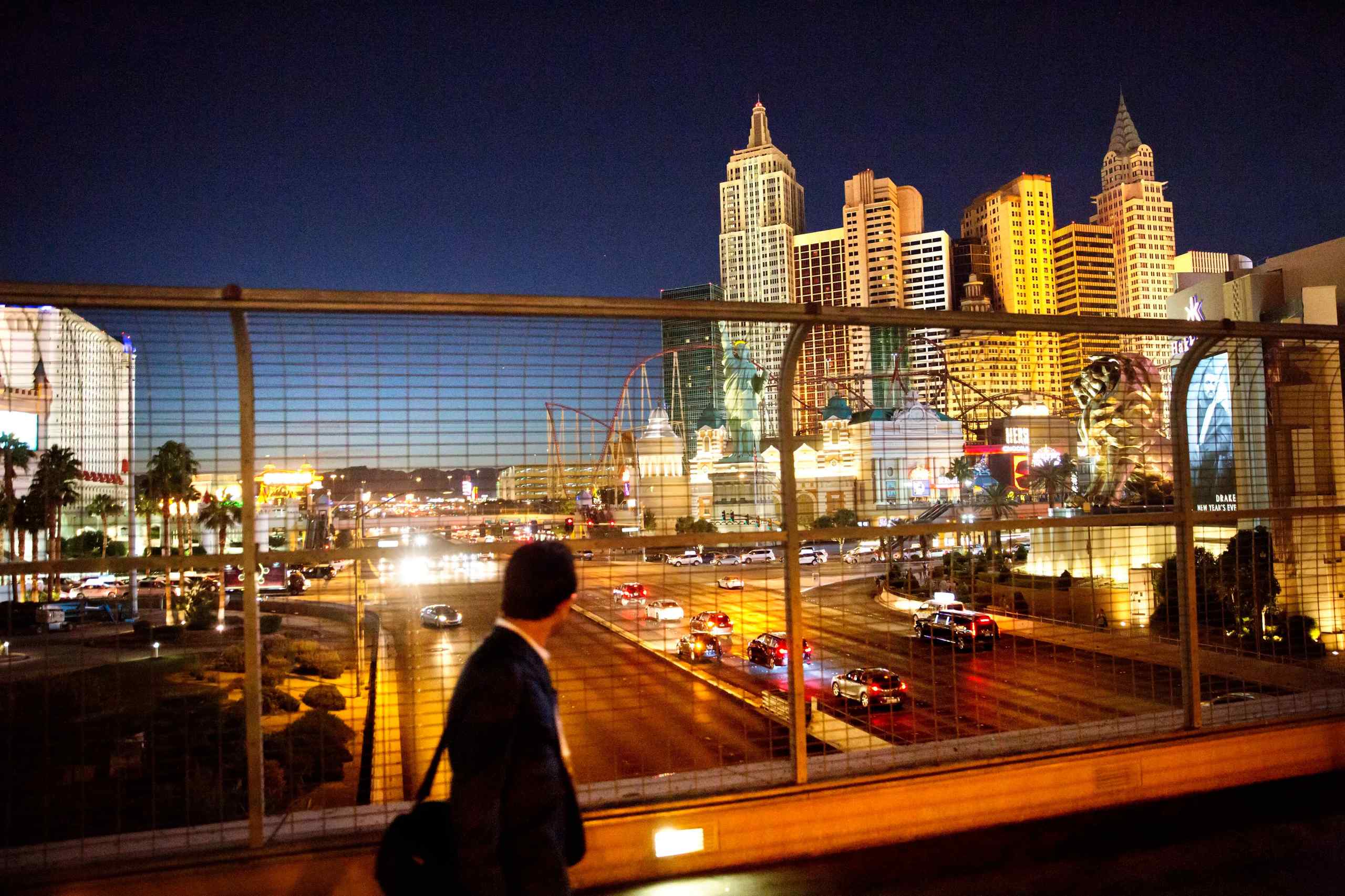 A man walks on an overpass while looking at Vegas.