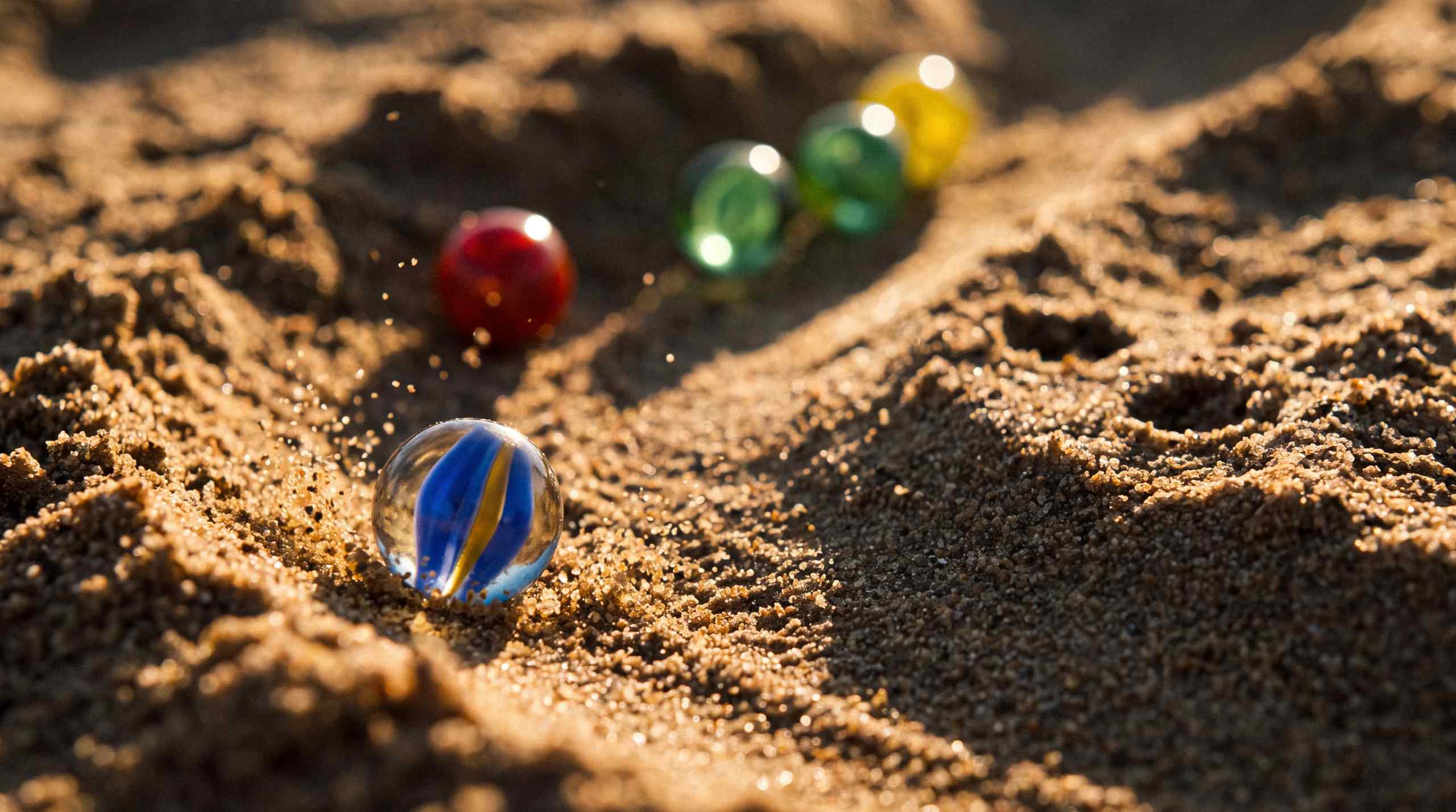 Marbles rolling down a sand track.