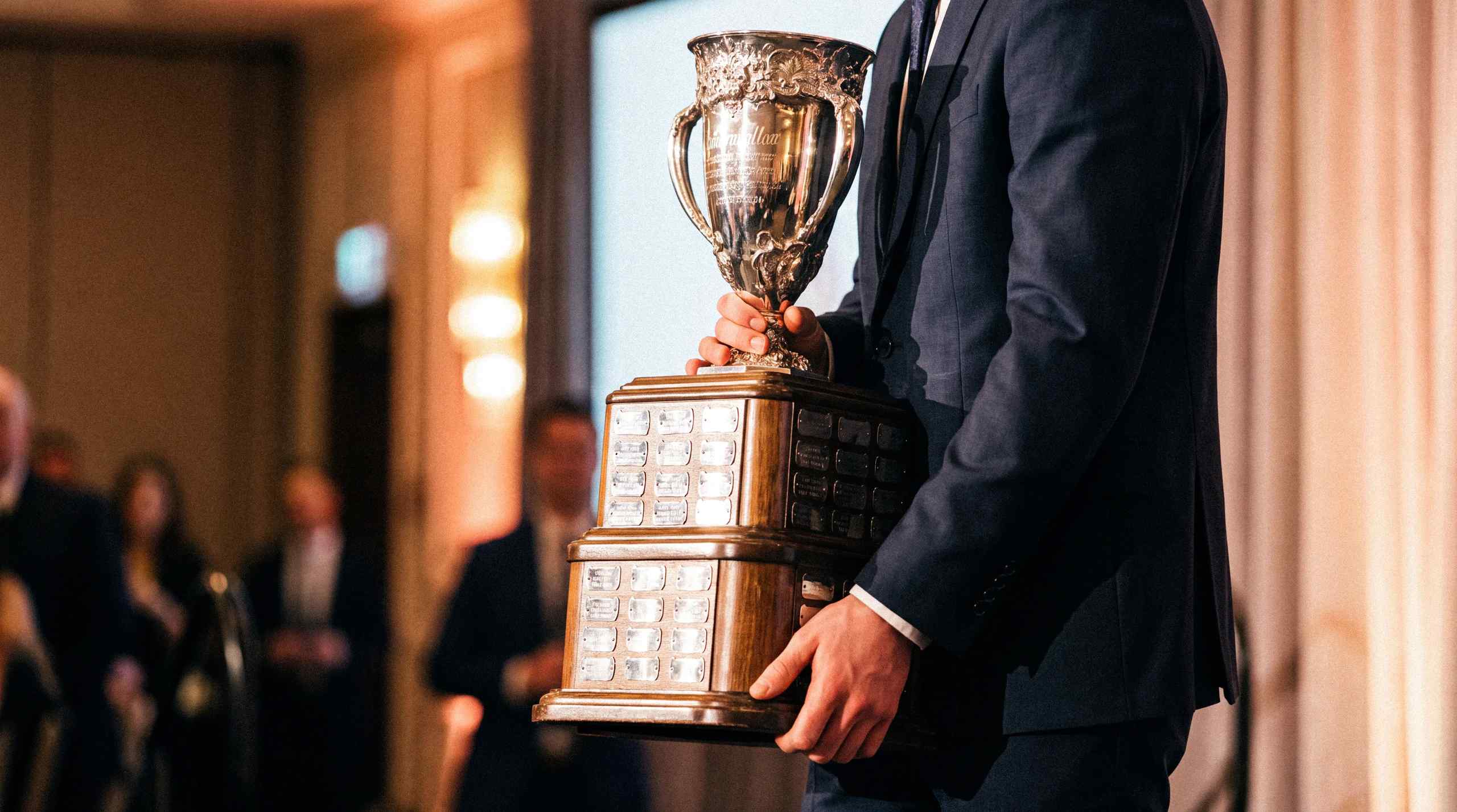 A man carrying the Calder Trophy, awarded to rookie of the year in the NHL