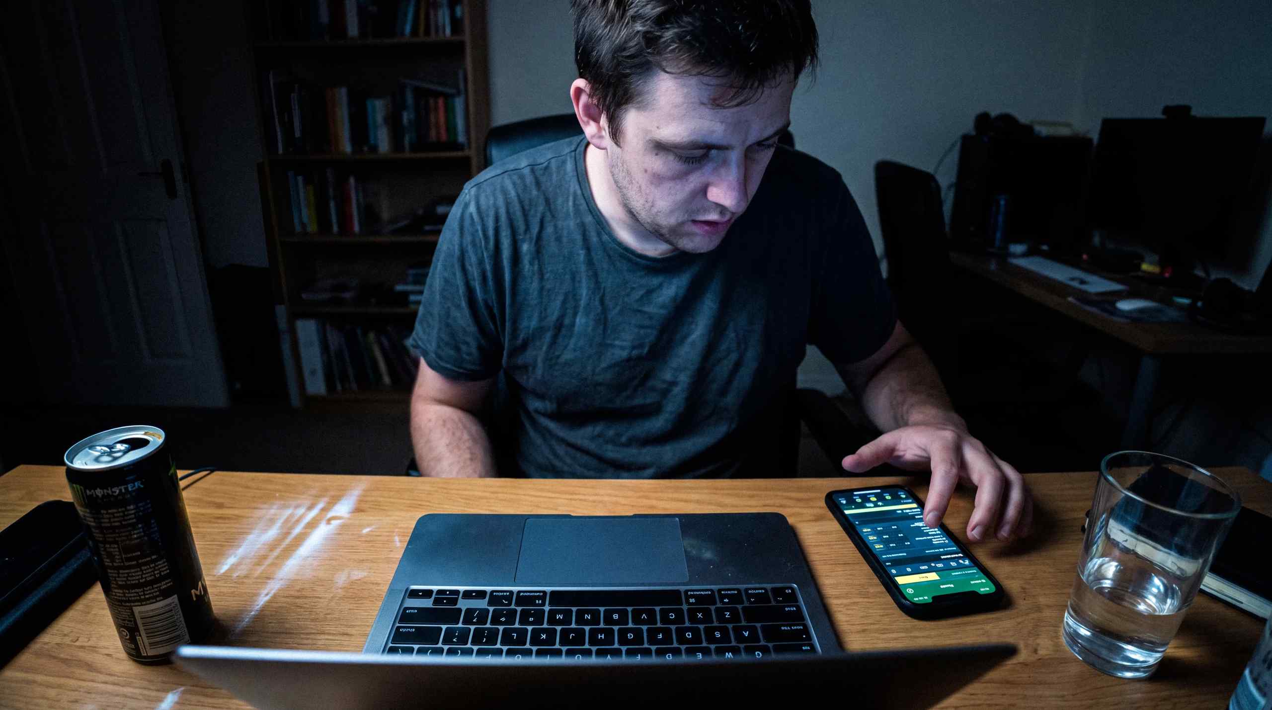 A man checking his wagers on his phone and laptop