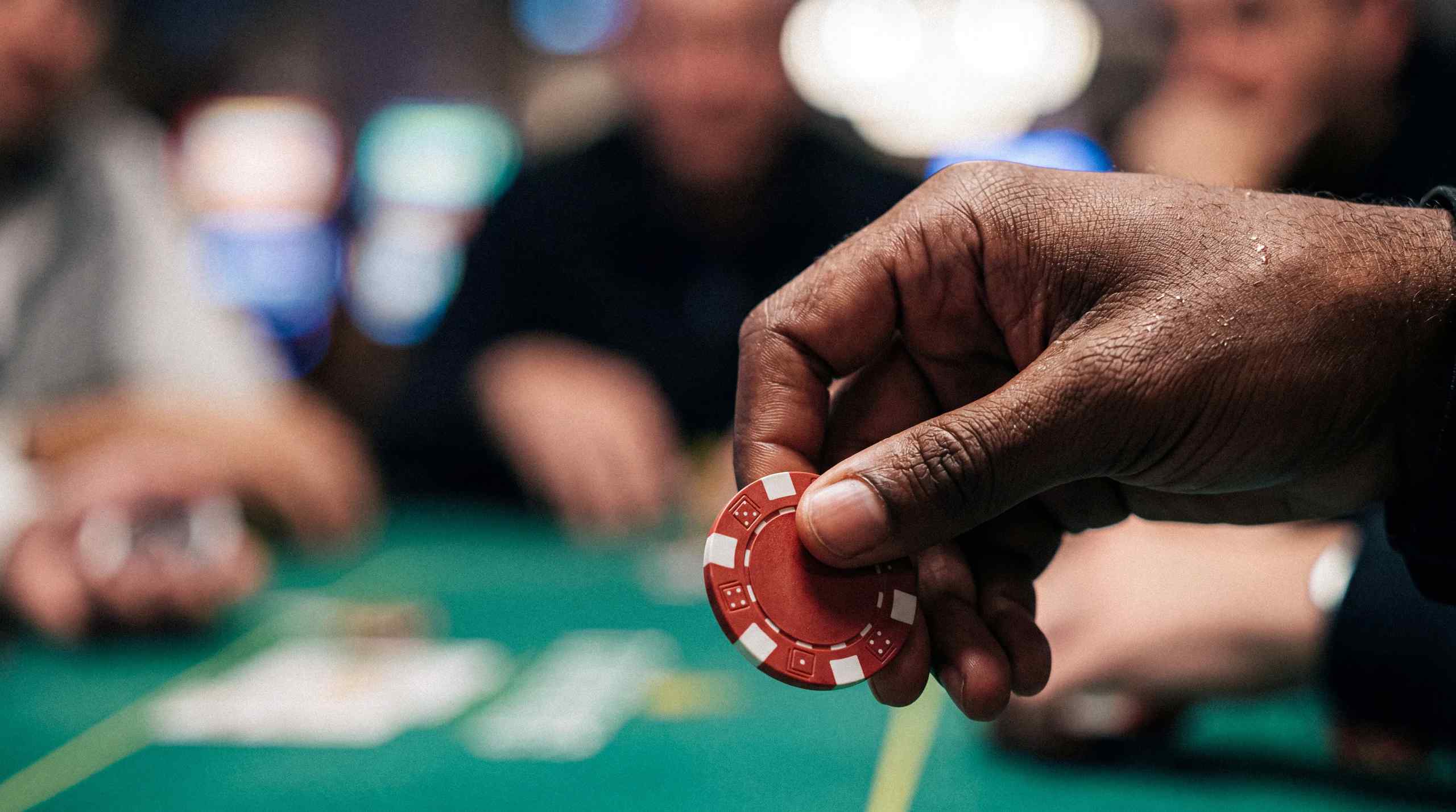 Close-up picture of a person holding a poker chip at a poker table. 